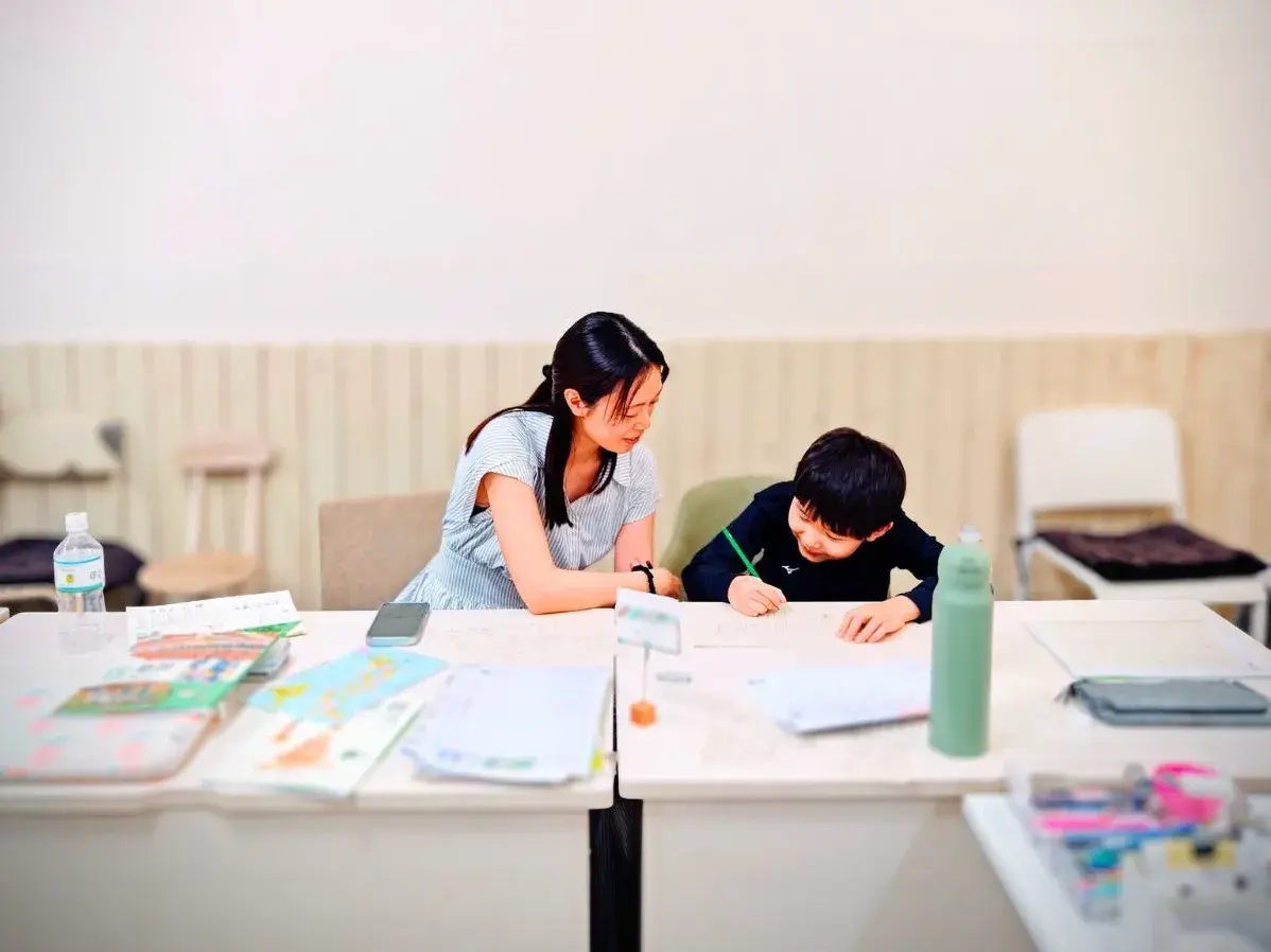 先生と一緒に机に向かって学習に取り組む様子