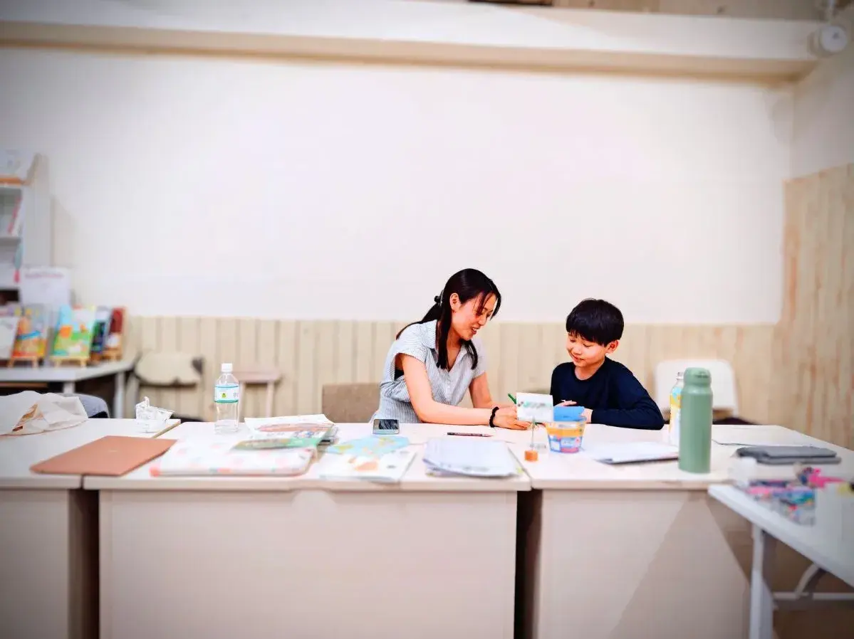 広々とした教室で先生と並んで学習に取り組む様子